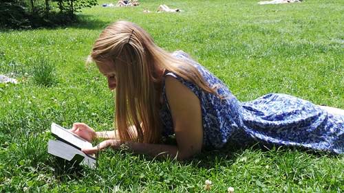 Girl Reading a Book on a Sunny Day in a Garden