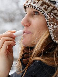 Woman Applying ChapStick to Her Lips to Treat Windburn
